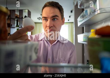 POV point of view from inside refrigerator Caucasian hungry man adult sad upset disappointed male. guy looking for good open empty fridge no food with Stock Photo