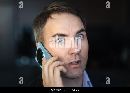 surprised businessman talking on mobile phone at home. Serious executive arguing on phone inside. Close up aggressive professional calling on cellphon Stock Photo