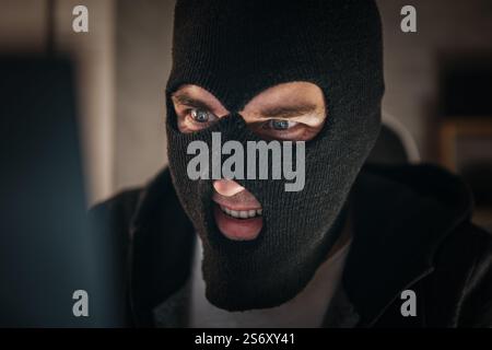 Thieves hold credit cards using a laptop computer for password hacking activities. Cyber crime concepts. a male thief holds a credit card in his hand Stock Photo