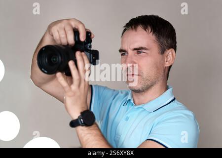 Photographer holding mirrorless camera for check his photo in selective focus. paparazzi, the photographer watches the subject through the camera. a y Stock Photo