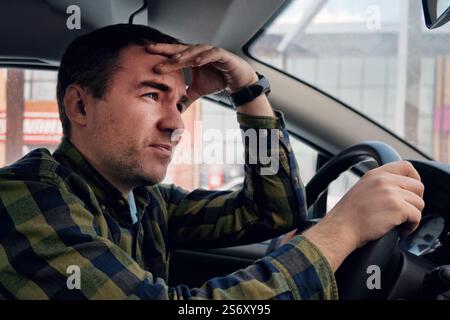 Close up picture of young pretty weary man waiting in car leaning on wheel. male feeling sleepy while waiting for somebody in his vehicle. Tired or de Stock Photo