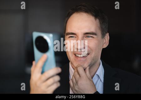 Businessman texting on his mobile phone sitting entering data with his thumbs and concentrating on screen Stock Photo