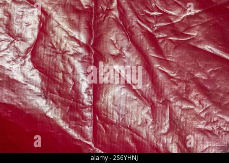 Shiny red frontlit of an old crumped banner, abstract background photo. Frontlit banner fabric laminated, made of polyester mesh with a special double Stock Photo