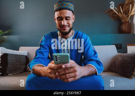 Moroccan guy with traditional outfit using smartphone. Stock Photo