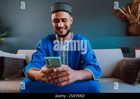 Moroccan guy with traditional outfit using smartphone. Stock Photo