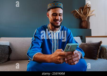 Moroccan guy with traditional outfit using smartphone. Stock Photo
