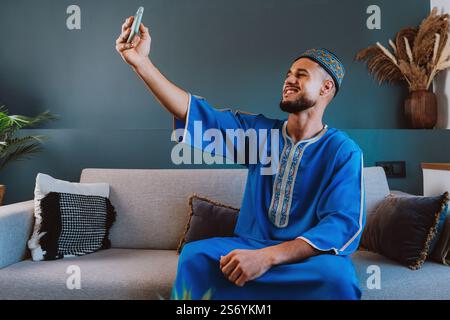Moroccan guy with traditional outfit using smartphone and taking selfies. Stock Photo