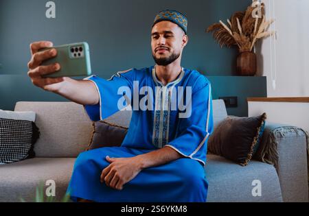 Moroccan guy with traditional outfit using smartphone and taking selfies. Stock Photo