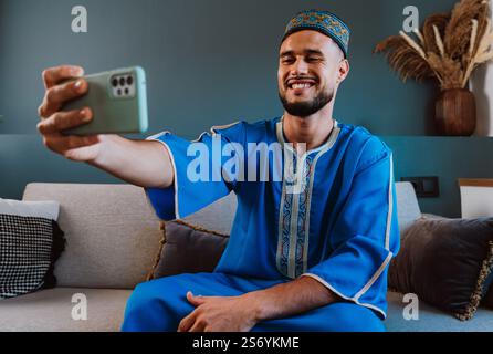 Moroccan guy with traditional outfit using smartphone and taking selfies. Stock Photo