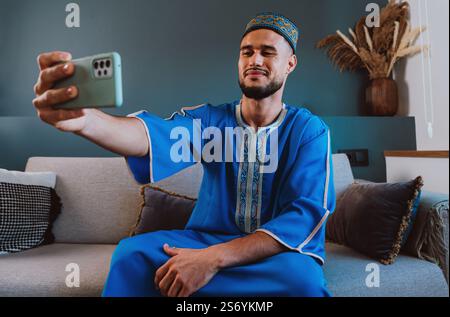 Moroccan guy with traditional outfit using smartphone and taking selfies. Stock Photo