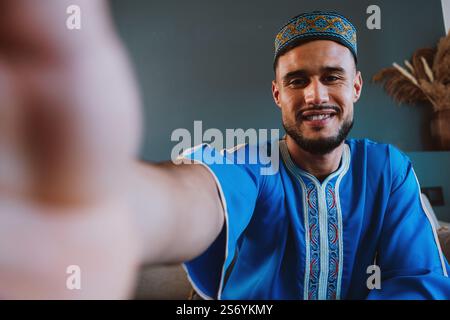 Moroccan guy with traditional outfit using smartphone and taking selfies. Stock Photo