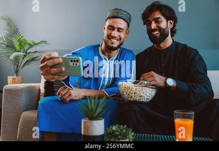 Two friends spending time together at home watching movies and eating popcorn. Stock Photo