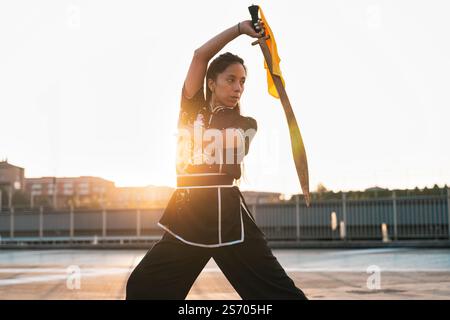 Chinese young woman practicing wushu kung fu with weapons outdoor. Young girl training martial arts form for the competition. Stock Photo