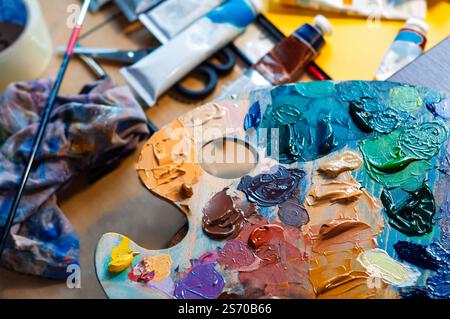 Close-up of a painters workspace featuring a colorful palette, tools, and paints. Stock Photo