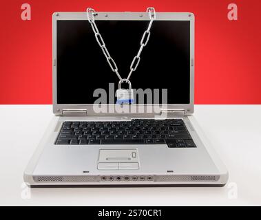 Laptop protected using a steel chain and padlock, symbolizing security and data protection. Stock Photo