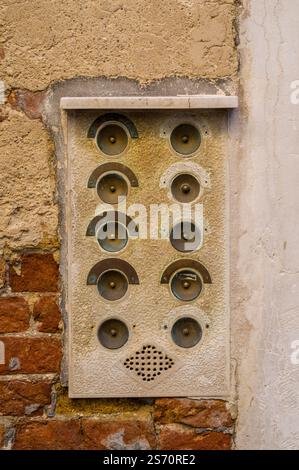 Vintage intercom with multiple buttons mounted on a stucco wall, part brick. Stock Photo