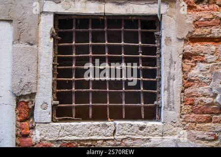 Rusty metal grate window in aged stone and brick wall.  Evidence of wear and time. Stock Photo