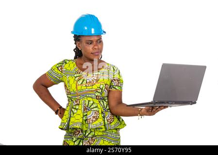beautiful young female engineer wearing safety helmet and working on laptop while smiling. Stock Photo