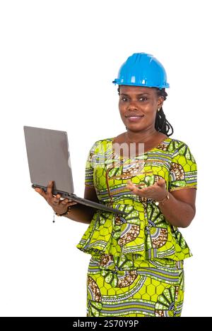 beautiful young female engineer wearing safety helmet and working on laptop while smiling. Stock Photo