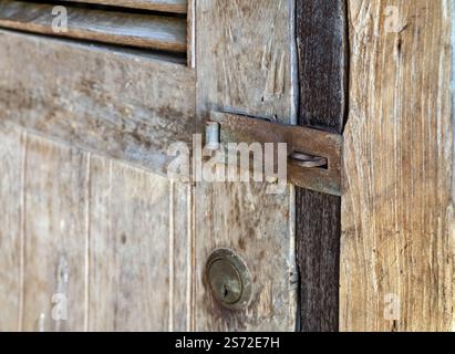Old rusty metal security Padlock Hasp and keyhole on brown old aged wooden door without lock. Stock Photo