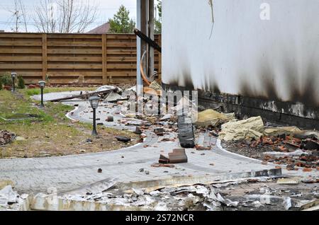 Aftermath of a devastating fire that destroyed a private home. Ruins of the house after the fire, debris from construction materials and rubbish scatt Stock Photo