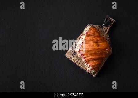 Crispy sweet red croissant with pistachio, raspberry and strawberry on a dark concrete background Stock Photo