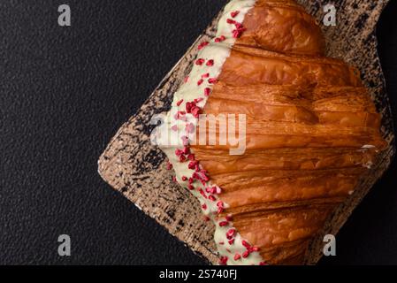Crispy sweet red croissant with pistachio, raspberry and strawberry on a dark concrete background Stock Photo