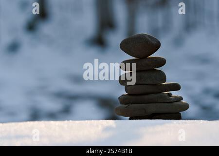 Zen balancing Stone tower on the bank of river in winter evening. River beach. Copy space. Stock Photo