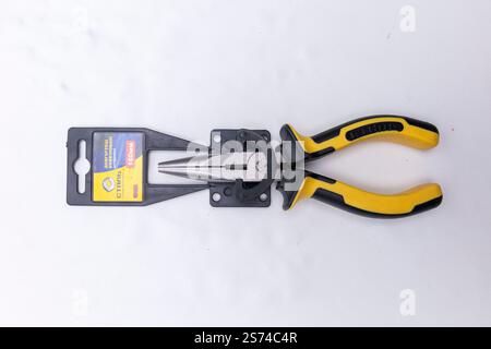 Combination pliers with yellow and black plastic handles on white background, ready for gripping, holding, and cutting Stock Photo