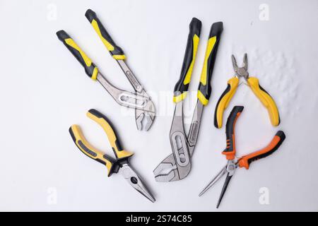 Groove joint pliers and different pliers with yellow and black or orange and black handles lying on a white background, ready for work Stock Photo