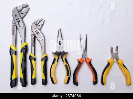 Different sizes of pliers and slip joint pliers lying on a white background, creating a gradient effect Stock Photo