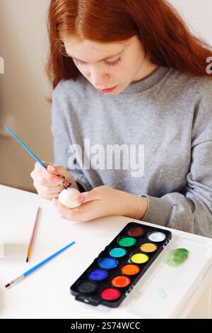 red hair girl paints easter eggs Stock Photo