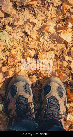 Hiking boots in golden fall autumn leaves with a soft orange yellow glow and copy space Stock Photo