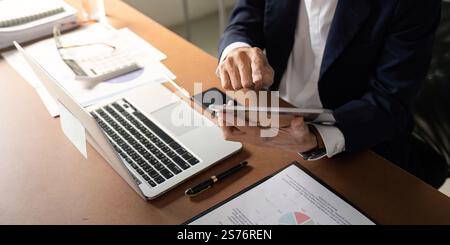 Elderly businessman analyzing data on a tablet while working in a modern office Stock Photo