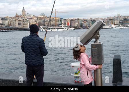 Istanbul, Turkey. 08th Jan, 2025. A man fishing and a child plays with street binoculars beside the Galata Bridge on the European side of Istanbul. With an ever expanding population in excess of 15 million people, Istanbul is the largest city in Turkey; spanning the continents of Europe and Asia is a dynamic economic and cultural hub and the former historical capital. Credit: SOPA Images Limited/Alamy Live News Stock Photo