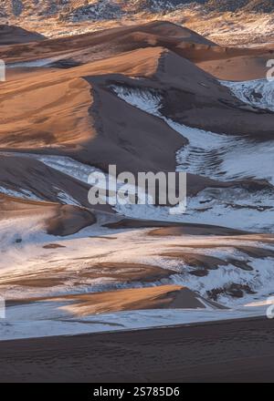 A close-up of snow-dusted sand dunes in Great Sand Dunes National Park, Colorado, highlighting textures and contrasts. A unique winter scene. Stock Photo