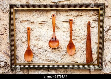 Rustic wooden utensils framed on textured stone wall. Stock Photo
