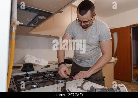 A Skilled Handyman Installing a Gas Stove in a Modern Kitchen. Stock Photo