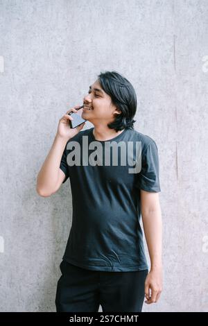 Young man engaged in a phone call, looking away thoughtfully. Stock Photo