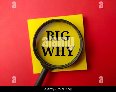 Top view magnifying glass and sticky note written with the text BIG WHY on a red background. Stock Photo