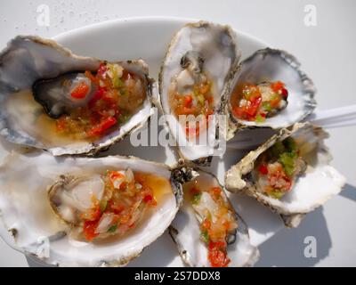 Steamed oysters with vegetables and vinegar in the shells. Gourmet seafood plate. Stock Photo