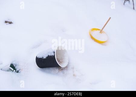 Disposable plastic cup with straw lying on snow Stock Photo