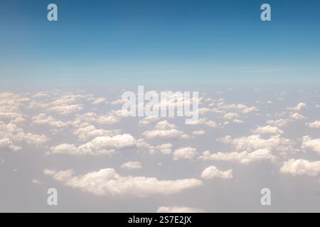 Puffy white clouds seen through plane window with sunny hazy blue sky, Africa Stock Photo