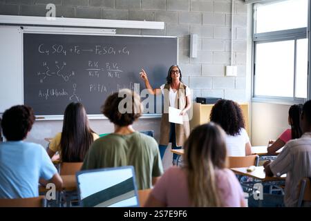 View from behind a group of multiracial students taking notes in a classroom Stock Photo