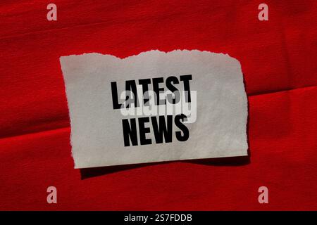 Latest news message written on ripped torn paper piece on red background. Conceptual latest news symbol. Copy space. Stock Photo
