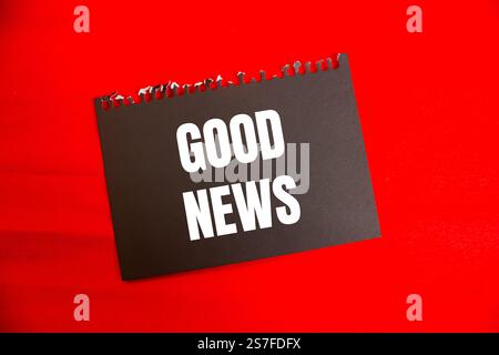 Good news message written on black paper with red background. Conceptual good news symbol. Copy space. Stock Photo