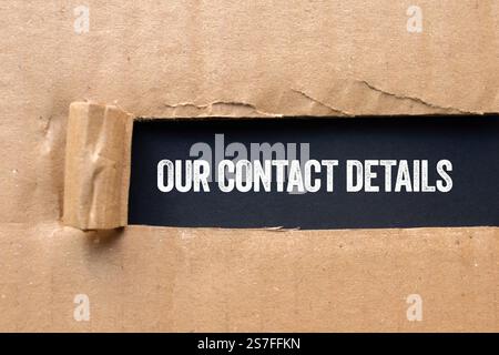 Our contact details message written on ripped torn cardboard paper on black background. Conceptual our contact details symbol. Copy space. Stock Photo