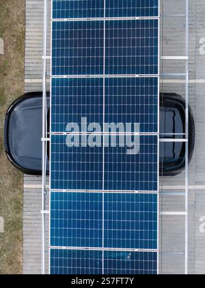Effective photovoltaic solar panel installation over a parked black vehicle in an urban area during daylight hours Stock Photo