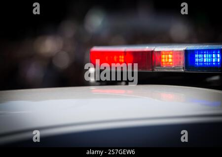 Close-up view of red and blue emergency lights on top of a police patrol vehicle at night. Stock Photo