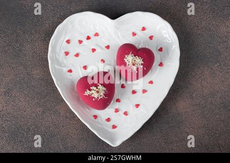 Bright mousse cakes Hearts with pink velour coating on heart-shaped plate for Valentines Day Stock Photo